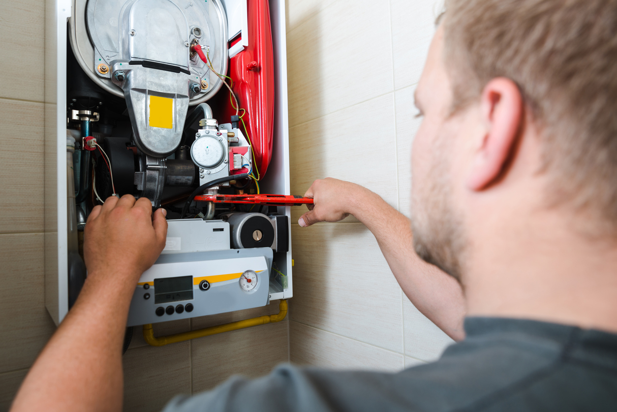 An HVAC technician using a wrench to repair a heating system.