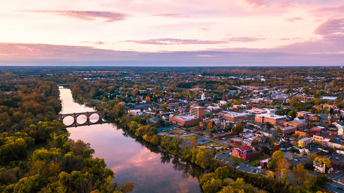 An aerial view of Fredericksburg, Virginia, and the surrounding areas with the Rappahannock River and the downtown area visible at sunrise.
